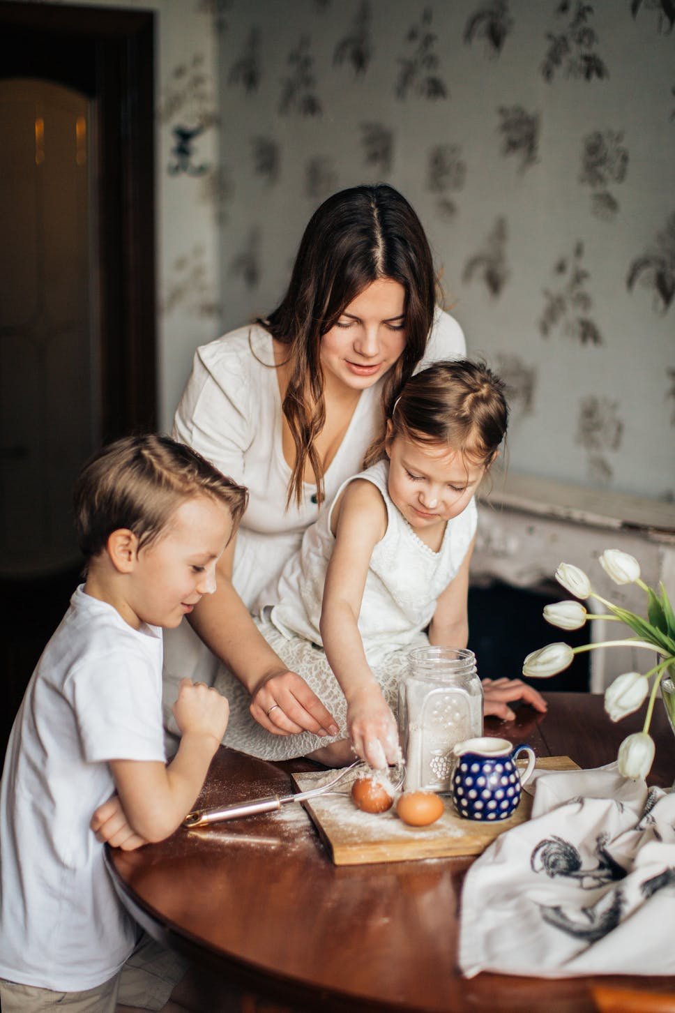 Woman with 2 children in the kitchen, floral wallpaper, tulips